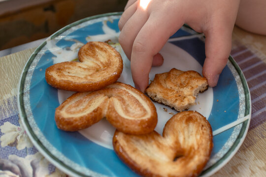 Bitten cookie in a child hand. The child takes a cookie from the plate