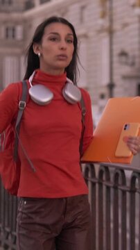Young female university student happily walking and dancing in the city