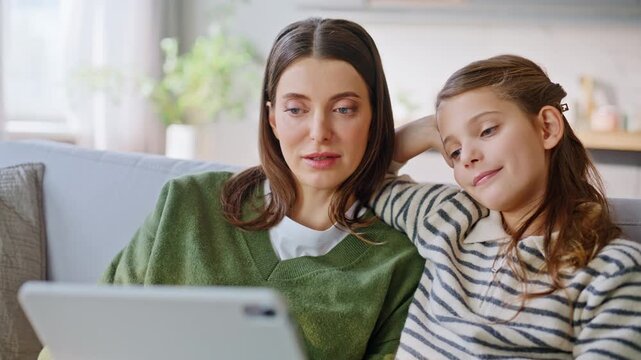 Aunt niece enjoying movie tablet computer chilling home sofa together closeup