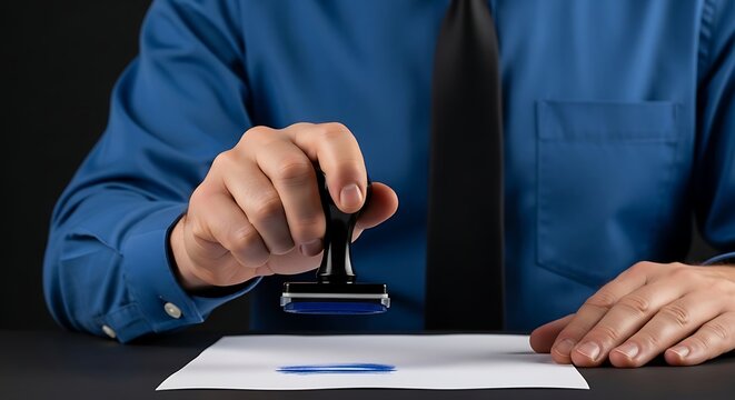 Man in blue shirt and black tie stamping blue ink on white paper with hand