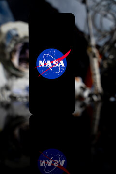 NASA logo displayed on a smartphone screen with a blurred image of planet Earth in the background, aerospace research and space exploration concept