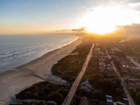 Aerial wide view of Bora Bora beach in Boraceia at sunset with people walking on wet sand mirror in Brazil