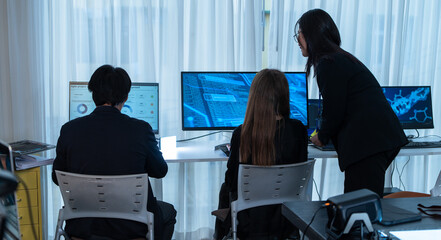 Rear view of a professional business team working on multiple computer monitors in a the office....