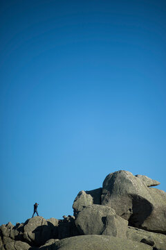 A man taking photographs while exploring thegranite rock formations of Monte Limbara, Tempio, Sardegna, Italia.
