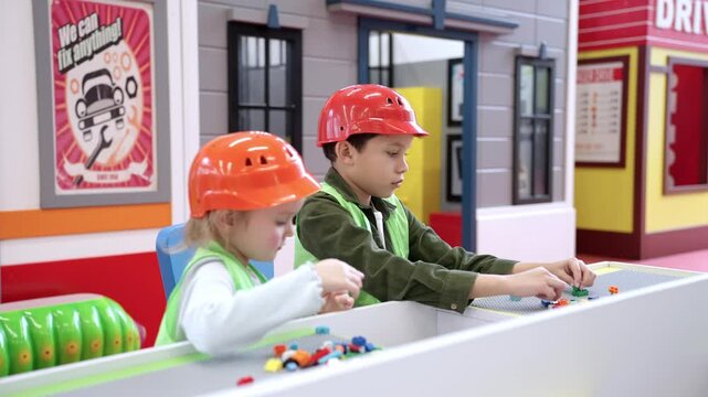 Children in helmets playing with toy colorful blocks of the children room. Kindergarten educational games. Slow motion