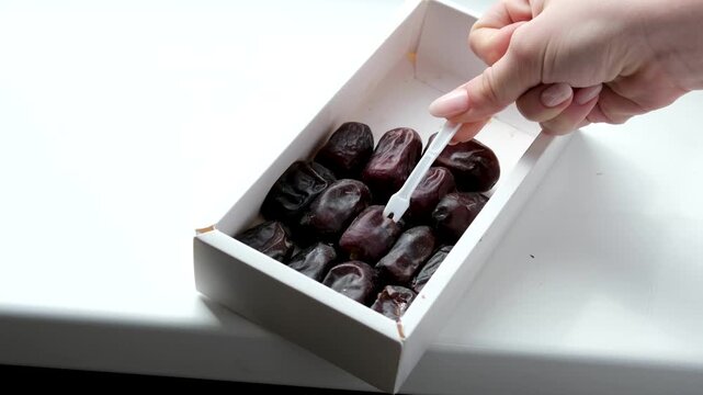 use a white plastic fork to remove dates from the box. High quality 4k footage