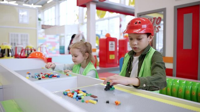 Little cute girl and African American boy playing with toy colorful blocks on the table of the game room. Kindergarten educational games. Slow motion