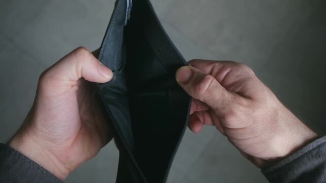 Male hands opening a black wallet to reveal that it is completely empty, a powerful visual metaphor for bankruptcy, unemployment, financial crisis, debt, and the rising cost of living