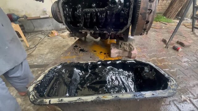 Seized Car Engine with Oil Sludge &ndash; Mechanic Inspecting Oil Pan and Engine Damage Close-Up, A mechanic&rsquo;s hand is seen inspecting the thick contaminated oil mixture, highlighting severe engine damage 
