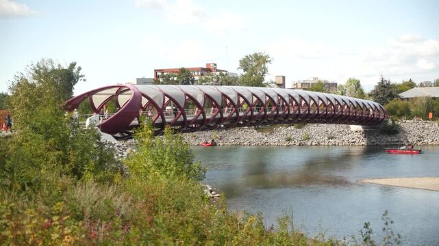 The Peace Bridge in Calgary, with its striking red design, welcomes pedestrians and cyclists as an iconic symbol of modern urban connection. High quality 4k footage