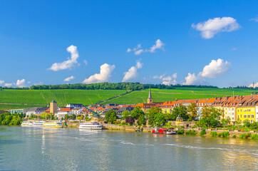 Fototapeta premium Wurzburg old town altstadt with old colorful houses on Main river embankment in Wurzburg city historical center Mitte, vineyards on green hill background in sunny summer day, Bavaria state, Germany