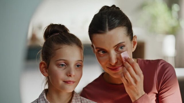 Makeup family looking mirror holding sponge closeup. Nanny pampering child face
