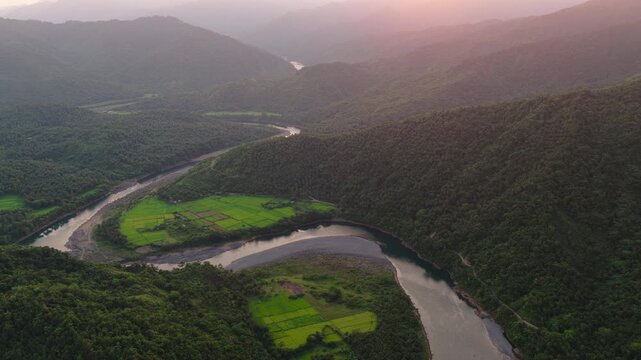 Scenic cinematic Panorama Aerial Drone video of the meandering blue Agos River, Valley, and Rice fields near Infanta, Quezon Province in Luzon, Philippines during Sunset