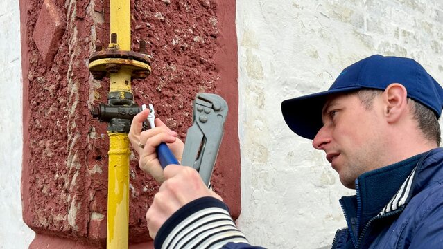 Gas fitter repairing outdoor pipeline with pipe wrench
