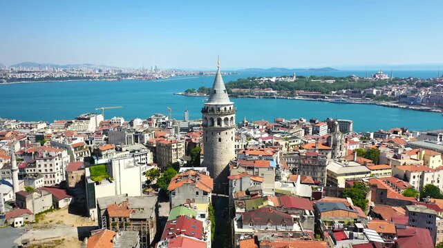 Galata Tower dominates the Beyoglu skyline in aerial view with Golden Horn, Hagia Sophia and Topkapi Palace peninsula visible, Istanbul. Aerial View