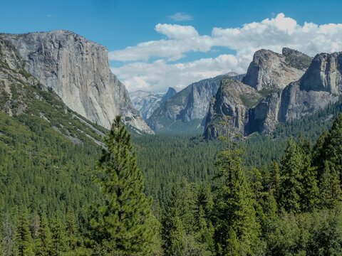 A scenic view of a blue sky, cliff, and mountain in Yosemite National Park.