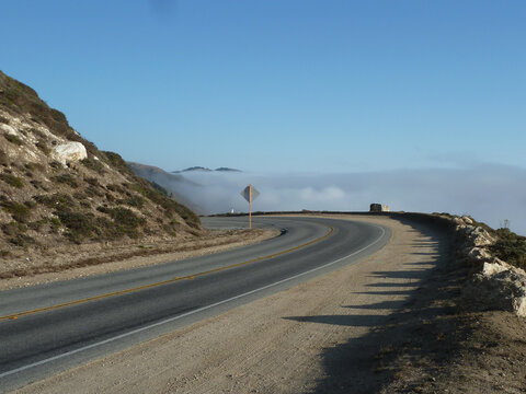 A scenic view of the Carmel area in the United States, featuring a blue sky, rocky hills, and a winding road.