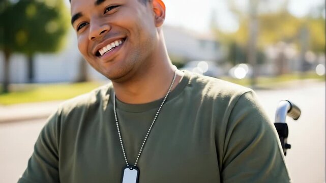 smiling hispanic veteran in wheelchair outdoors. disabled soldier wearing military dog tags and olive t-shirt. happy man recovering. disability support concept.