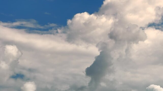 Massive white cumulus clouds billowing vertically against blue sky filling the frame in cinematic time lapse