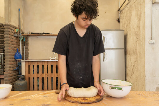 Young man preparing homemade bread or pizza in a kitchen