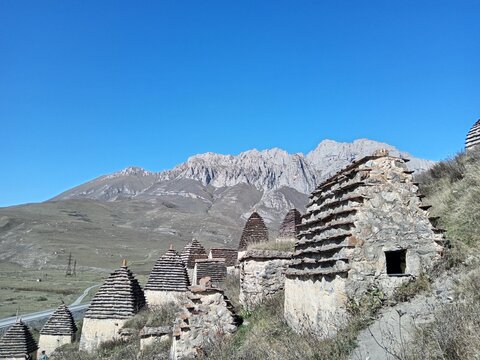 Panoramic view of Dargavs City of the Dead, North Ossetia, Russia. Dozens of ancient crypts rising from the grass in a quiet mountain valley.