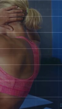Woman in pink sports bra crunching in gym, closing eyes and securing hair tie, partner following
