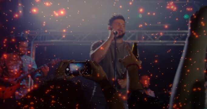 Concert starting when fan raising phone singer singing into mic sparkles pulsing crowd filming show