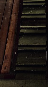 A close-up image of the wall of an old wooden house, more than a century old, reveals the texture, cracks, and dust and cobwebs that have been left untouched by time, reflecting the historical archi