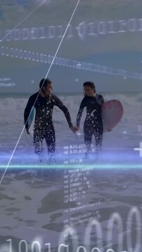 Vertical video: Couple returning to shore, stepping toward camera with boards, binary data on suits