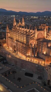 Illuminated Cathedral of Santa Maria in Palma at night, vertical aerial view of the historic landmark in Mallorca. Stunning twilight over the La Seu cathedral in Spain