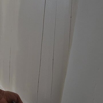 Professional construction worker applying thin coat plaster on a new apartment wall.