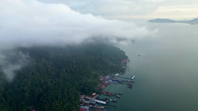 Aerial view of Pulau Pangkor, morning mist drifting over green hills and turquoise waters.