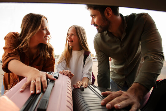 European family enjoying moment loading their luggage into the trunk of car, preparing for journey on holidays