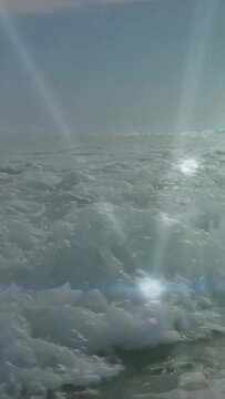 Vertical video: Nodes popping, net shifting while surf rolling and foaming, showing sun reflection
