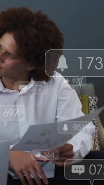 Vertical video: Man holding document on sofa reacting to rising business alerts, glancing left