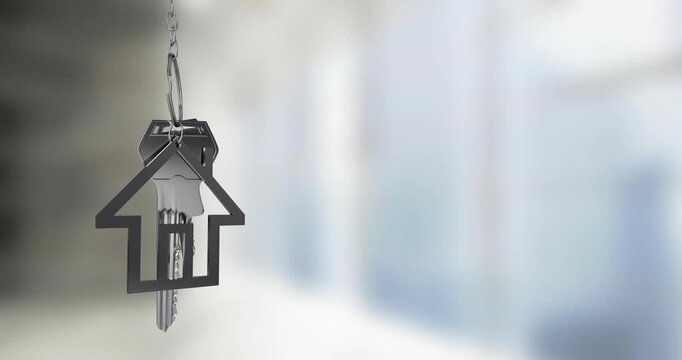 House-shaped keychain with keys hanging over blurred background