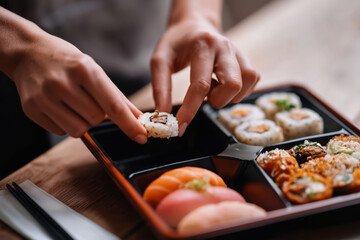 Fototapeta premium Expert hands selecting sushi rolls from a beautifully arranged platter