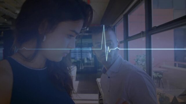 Animation of illuminated heart rhythm over diverse coworkers discussing in office