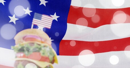 Displaying stacked cheeseburger with sesame bun and US flag toothpick on flag backdrop, copy space © vectorfusionart
