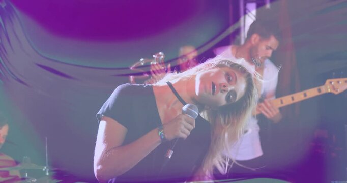 Cam rising low-to-head, singer performing music with mic, tossing hair under purple or green overlay