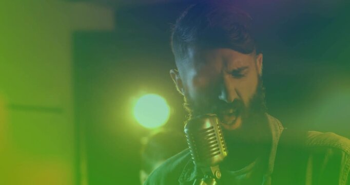 Lead singer stepping to vintage mic, singing to drive music rehearsal as camera pushing in