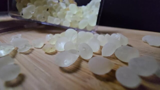 Macro shot of premium Mastic gum (Pistacia lentiscus) tears on a wooden surface. High-quality footage showcasing the translucent, pale yellow resin used in medicine and cooking.