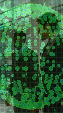 Vertical video: Two staff passing in business atrium as green data overlay appearing over staff