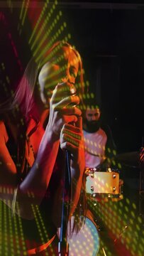 Vertical video: Lead singer gripping mic, singing for music while dotted lights sweeping over band