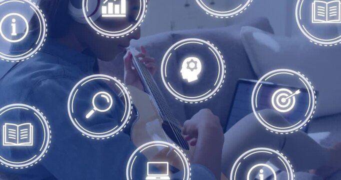 Female musician following laptop lesson, playing guitar while learning icons fading and overlapping