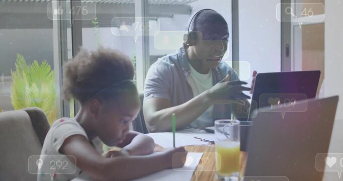 Dad on work call gesturing, causing animated social icons over laptop while girl writing homework