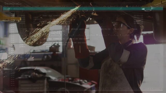 Starting tech grinding metal with corded grinder under car lift bay, wearing PPE, data overlay