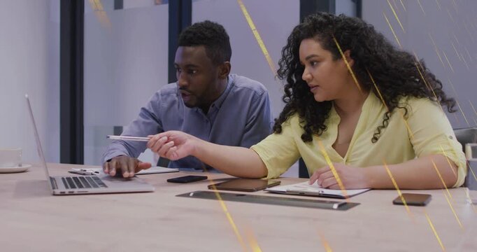 Female coworker reaching and pointing pen, male coworker using laptop controls for project review