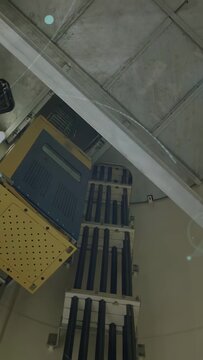 Vertical video: Camera tilting, cable tray centering lens flares growing to reveal gear for check