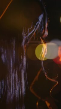 Vertical video: Keyboardist pressing keys and leaning to music, moving bokeh lights and guitar